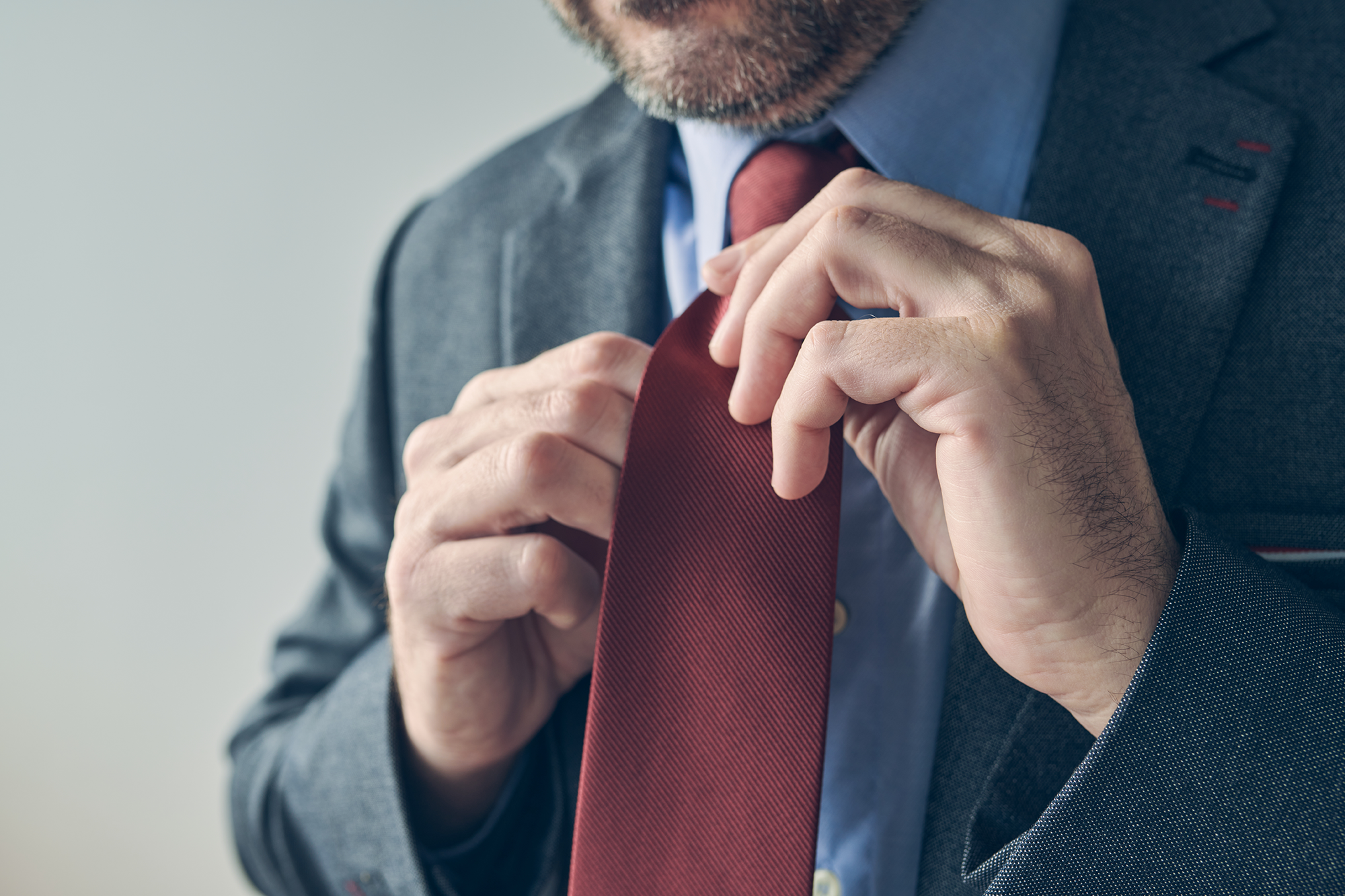 Man in suit fixing solid red necktie